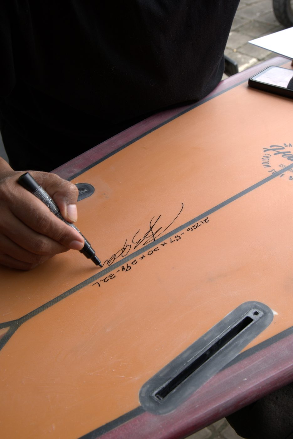 Budi signing a custom board with the client's dimensions