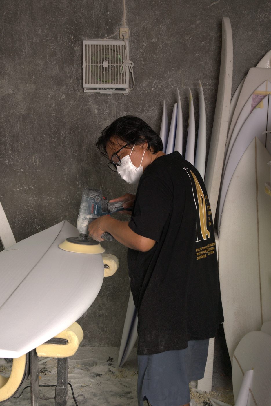 Budi in his workshop surrounded by finished boards
